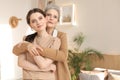 Beautiful mother and daughter. Cheerful young woman is embracing her middle aged mother in living room. Family portrait. Royalty Free Stock Photo