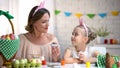 Beautiful mother and daughter in funny headbands eating Easter chocolate eggs Royalty Free Stock Photo