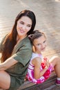 Beautiful mother and daughter sitting outdoors on steps and laughting