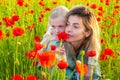 Beautiful mother and daughter in spring poppy flower field. Mom holds her child daughter in the flowering meadow. Spring Royalty Free Stock Photo