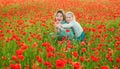 Beautiful mother and daughter in spring poppy flower field. Mom holds her child daughter in the flowering meadow Royalty Free Stock Photo