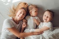 Beautiful mother having fun with her sons in bed in the morning