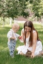 beautiful mother and her baby son playing with striped cat in the sunny summer park. mothers, baby's day. happy Royalty Free Stock Photo