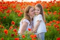 Beautiful mother and her daughter in spring poppy flower field, Czech republic Royalty Free Stock Photo