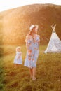 Beautiful mother with her little daughter having fun near wigwam in the field. Spending time together, outside, on vacation, Royalty Free Stock Photo