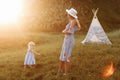 Beautiful mother with her little daughter having fun near wigwam in the field. Spending time together  outside  on vacation Royalty Free Stock Photo