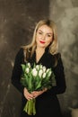 Beautiful mother hold a bouquet of white tulips on 8th of march. Flowers in woman`s hand. Blond hair mom with flowers at Royalty Free Stock Photo