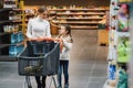 Beautiful mother holding grocery basket with her child walking in supermarket. Shopping for healthy Royalty Free Stock Photo