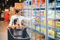 Beautiful mother holding grocery basket with her child walking in supermarket. Shopping for healthy Royalty Free Stock Photo