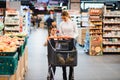 Beautiful mother holding grocery basket with her child walking in supermarket. Shopping for healthy Royalty Free Stock Photo