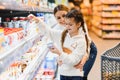 Beautiful mother holding grocery basket with her child walking in supermarket. Shopping for healthy Royalty Free Stock Photo