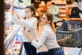 Beautiful mother holding grocery basket with her child walking in supermarket. Shopping for healthy Royalty Free Stock Photo