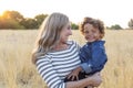 Beautiful Mother holding her adorable curly haired son in the outdoor sunlight Royalty Free Stock Photo