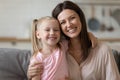 Beautiful mother hug daughter family sitting indoors looking at camera