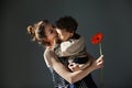 Beautiful Mother hugs son, kisses tenderly and holds gerbera flower in hand. Authentic portrait of real family, sunny