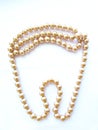 Beautiful mother-of-pearl round light beige large beads on a tooth-shaped thread isolated object on a white background