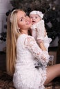 Beautiful mother posing with her cute little baby girl beside Christmas tree Royalty Free Stock Photo