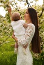 Beautiful mother posing with her little cute baby in blossom garden Royalty Free Stock Photo