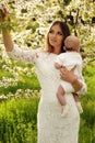 Beautiful mother posing with her little cute baby in blossom garden Royalty Free Stock Photo