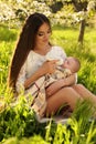 Beautiful mother posing with her little cute baby in blossom garden Royalty Free Stock Photo