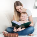 Beautiful mother reading big book to her smiling baby boy Royalty Free Stock Photo