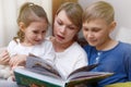 Beautiful mother is reading a book to her young children. Sister and brother is listening to a story. Royalty Free Stock Photo
