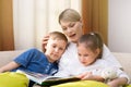 Beautiful mother is reading a book to her young children. Sister and brother is listening to a story.