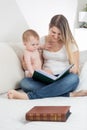 Beautiful mother showing images in old book to her 9 months old Royalty Free Stock Photo
