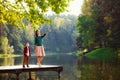 A beautiful mother stands on a lake bridge and points something out to her son with a beautiful landscape of nature Royalty Free Stock Photo