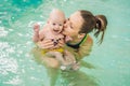 Beautiful mother teaching cute baby girl how to swim in a swimming pool. Child having fun in water with mom Royalty Free Stock Photo