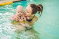 Beautiful mother teaching cute baby girl how to swim in a swimming pool. Child having fun in water with mom Royalty Free Stock Photo