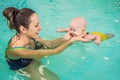 Beautiful mother teaching cute baby girl how to swim in a swimming pool. Child having fun in water with mom Royalty Free Stock Photo