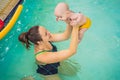 Beautiful mother teaching cute baby girl how to swim in a swimming pool. Child having fun in water with mom Royalty Free Stock Photo