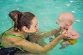 Beautiful mother teaching cute baby girl how to swim in a swimming pool. Child having fun in water with mom Royalty Free Stock Photo