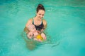 Beautiful mother teaching cute baby girl how to swim in a swimming pool. Child having fun in water with mom Royalty Free Stock Photo