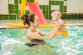 Beautiful mother teaching cute baby girl how to swim in a swimming pool. Child having fun in water with mom Royalty Free Stock Photo