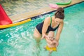 Beautiful mother teaching cute baby girl how to swim in a swimming pool. Child having fun in water with mom Royalty Free Stock Photo