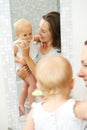 Beautiful mother teaching cute baby how to brush teeth Royalty Free Stock Photo