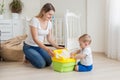 Beautiful young mother teaching her 10 months old son using baby pot Royalty Free Stock Photo