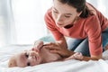 Mother touching cute infant baby lying on bed Royalty Free Stock Photo