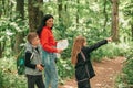 Beautiful mother with two kids hiking in a forest, looking at a map and pointing with hand Royalty Free Stock Photo