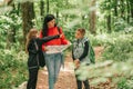 Beautiful mother with two kids are walking through forest, using a map and planning a hiking adventure Royalty Free Stock Photo