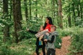 Beautiful mother with two kids are walking through forest, using a map and planning a hiking route Royalty Free Stock Photo
