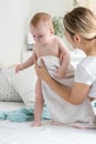 Beautiful young mother wiping her wet baby with towel after washing in bath