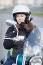 Beautiful motorcyclist Caucasian woman trying on white helmet while sitting on bike and looking at back mirror