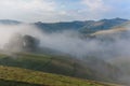 Beautiful mountain landscape of a foggy morning with and old house, trees and clouds Royalty Free Stock Photo