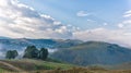 Beautiful mountain landscape of a foggy morning with and old house, trees and clouds Royalty Free Stock Photo