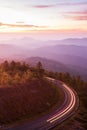 Beautiful mountain road at sunrise, curve asphalt road with light trail from headlights leading through mountain range. Doi Royalty Free Stock Photo