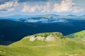 A beautiful mountain scenery. A dramatic, blue sky with many clouds. The heights of the mountains covered with green grass and Royalty Free Stock Photo