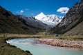 Beautiful mountain valley with show-capped peaks and a turquoise mountain stream in the foreground